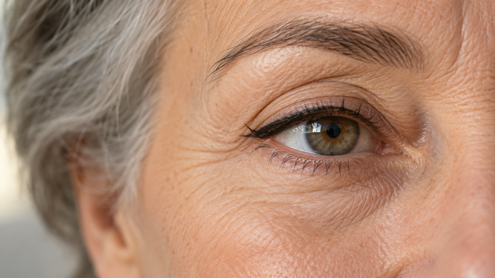 Close-up of an older woman's eye with subtle eyeliner applied along the upper lash line
